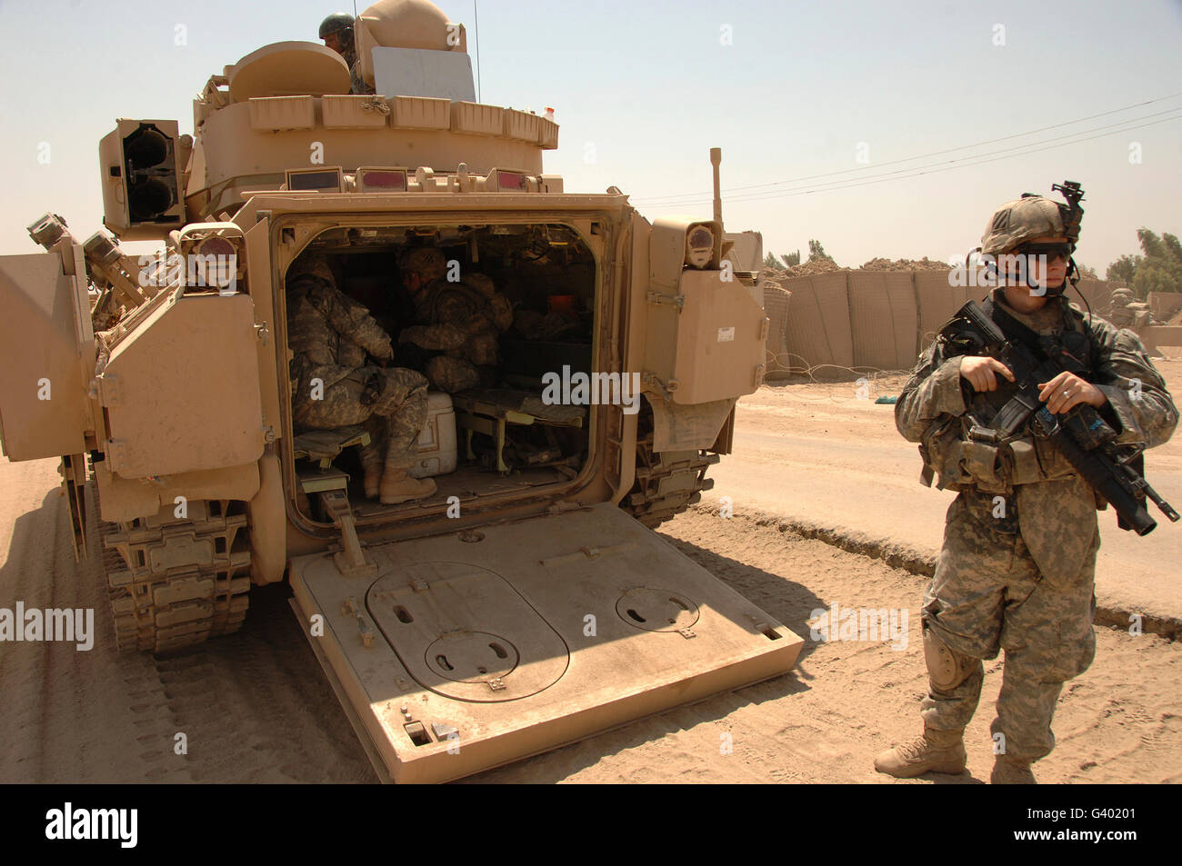 Soldiers climb into the back of a M2 Bradley Fighting Vehicle. Stock Photo