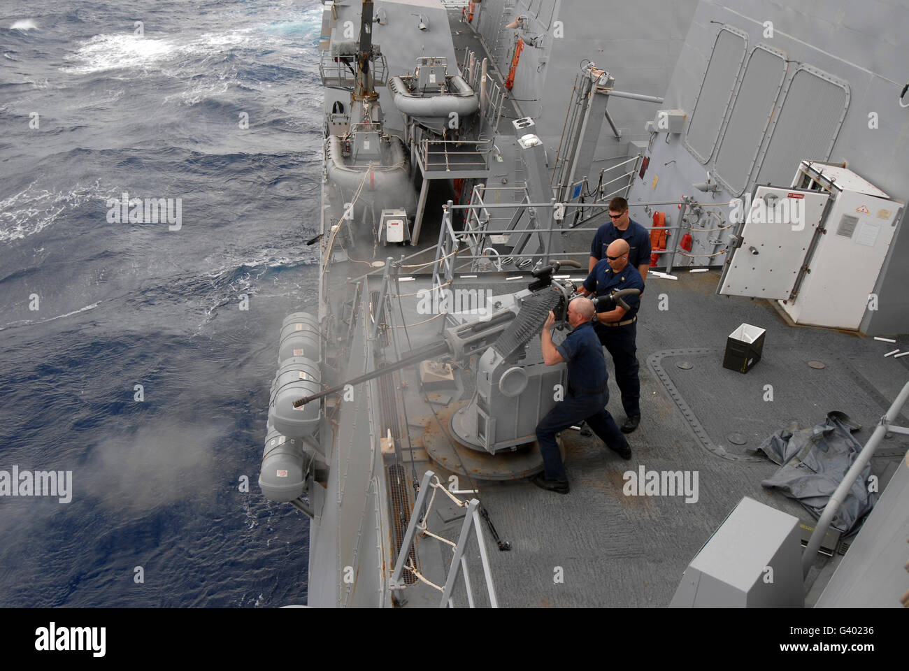 Sailors fire a Mark 38 machine gun board guided missile destroyer USS Nitze. Stock Photo
