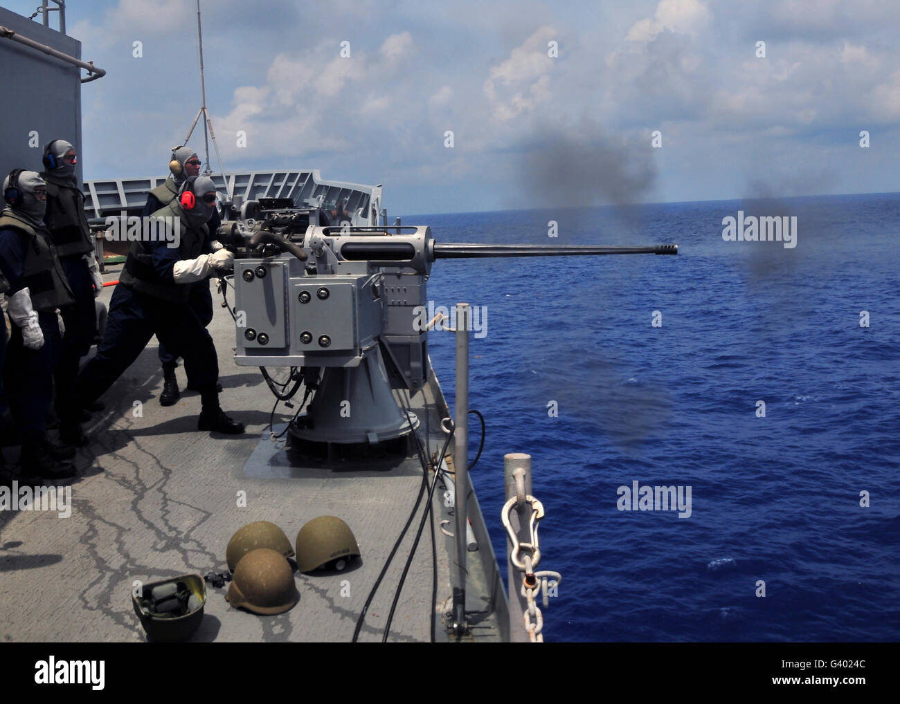 Gunner fires a Mark 38 machine gun aboard USS Frank Cable. Stock Photo