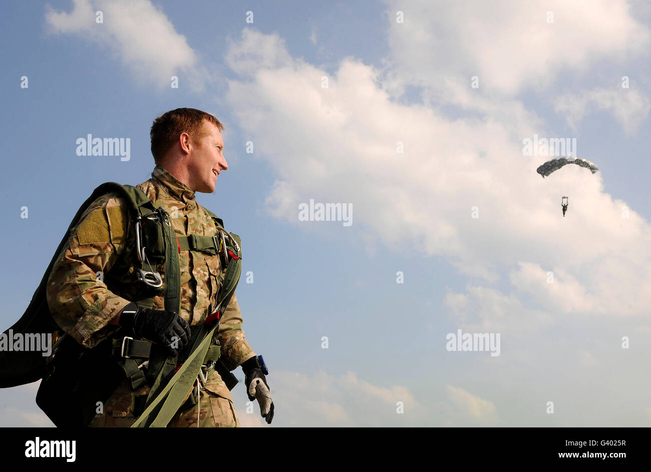 A paratrooper looks on as other paratroopers parachute down in Cheongju, South Korea. Stock Photo