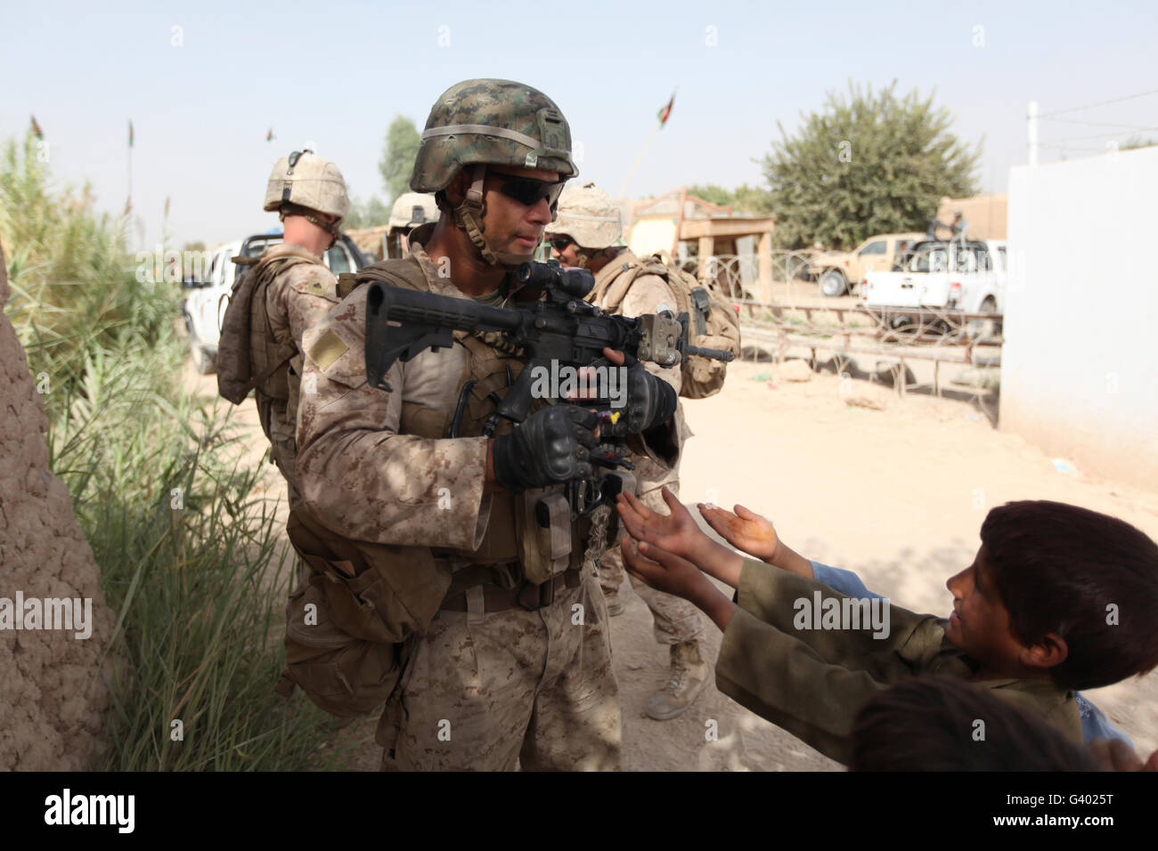 A U.S. Marine gives a piece of candy to an Afghan boy during a patrol. Stock Photo