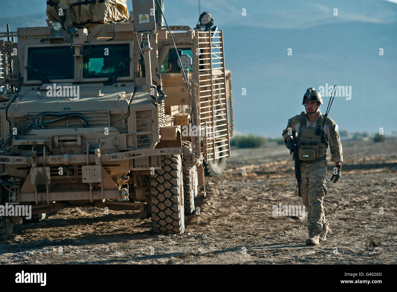 U.S. Air Force Joint Terminal Attack Controller walks past a MRAP vehicle while on patrol. Stock Photo