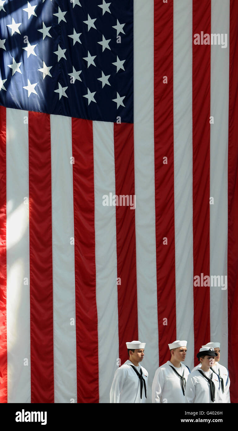 Sailors stand in front of the American flag ready to sing the Navy Hymn. Stock Photo