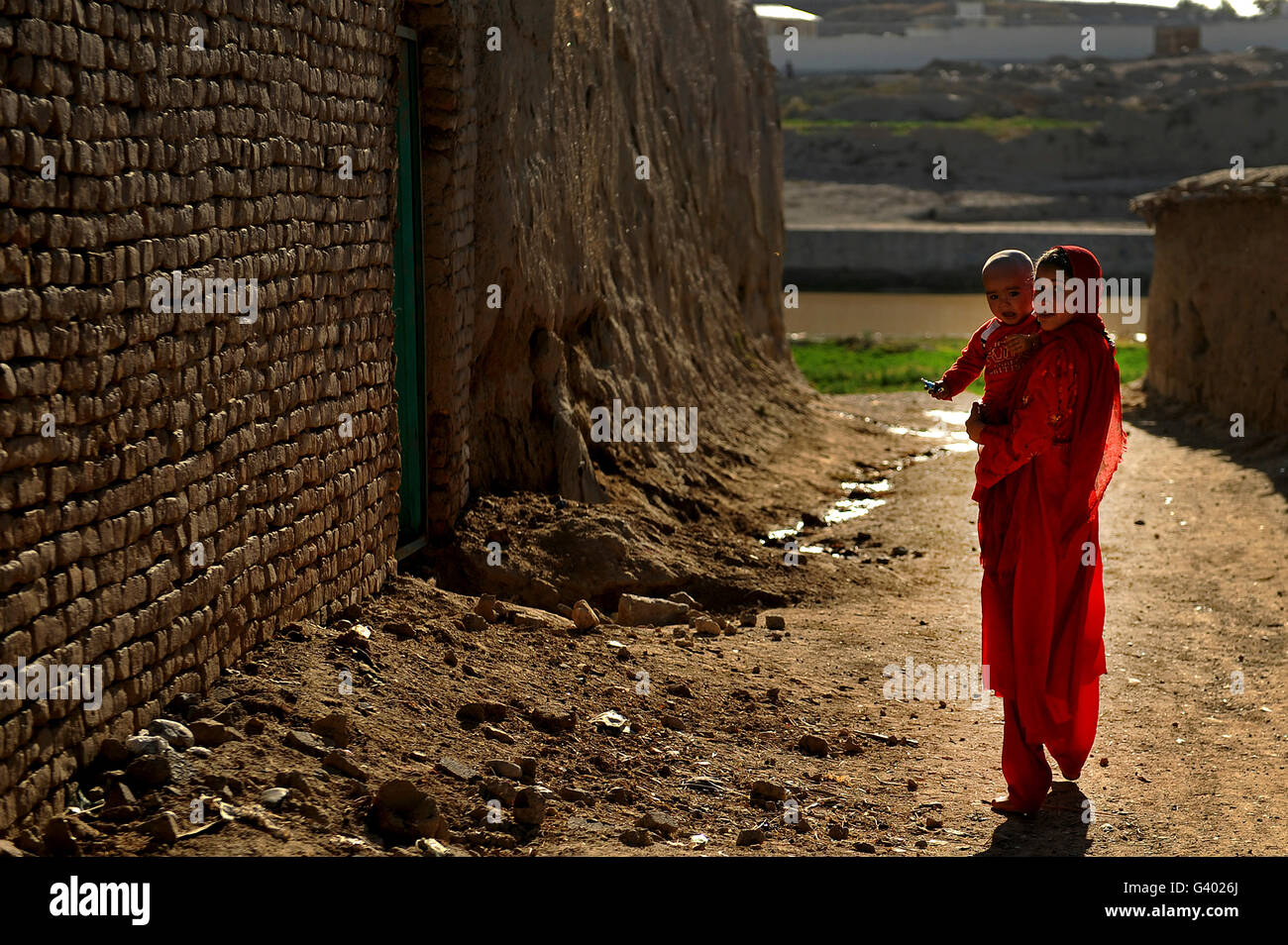 An Afghan girl carries her little brother to their home in Qalat, Afghanistan. Stock Photo