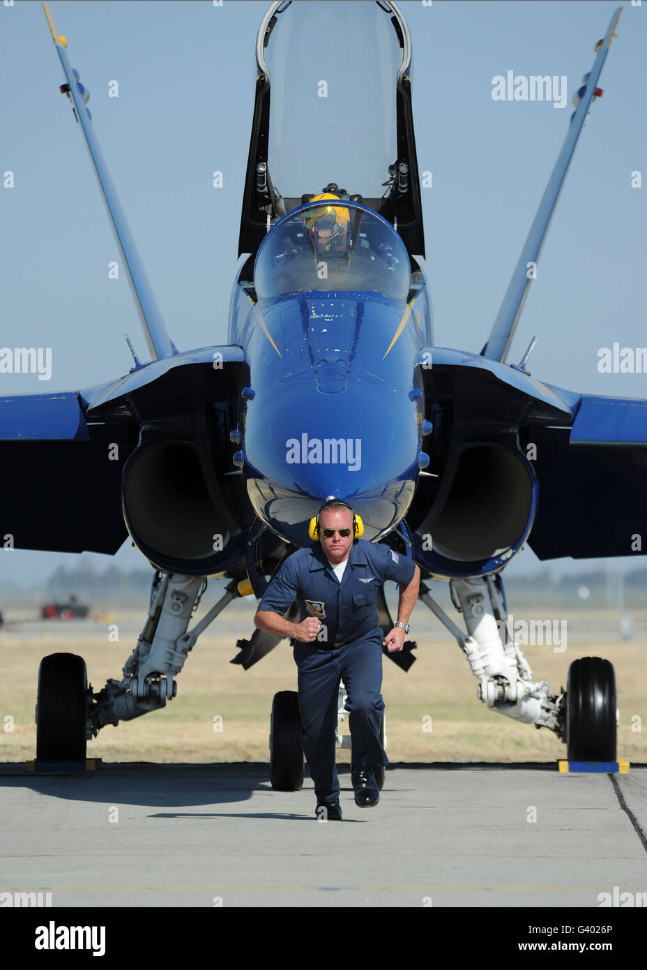 A crew chief sprints ahead of a Blue Angels F/A-18 aircraft. Stock Photo