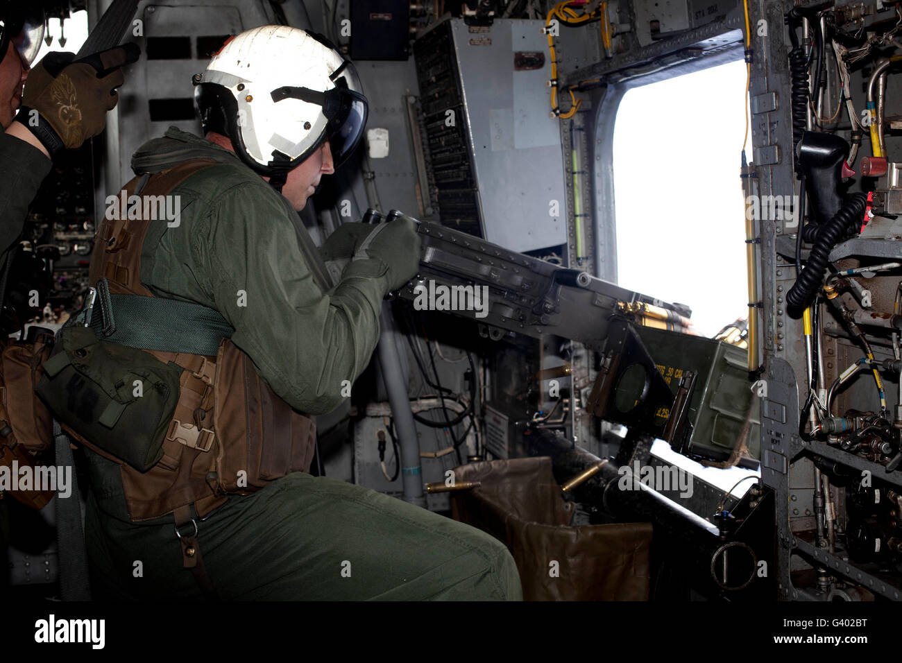 Crew chief fires an M2 .50-caliber heavy machine gun from a CH-53E Super Stallion. Stock Photo