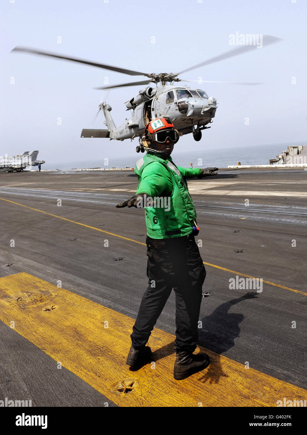 Airman checks the takeoff path of a hovering SH-60F Sea Hawk helicopter. Stock Photo