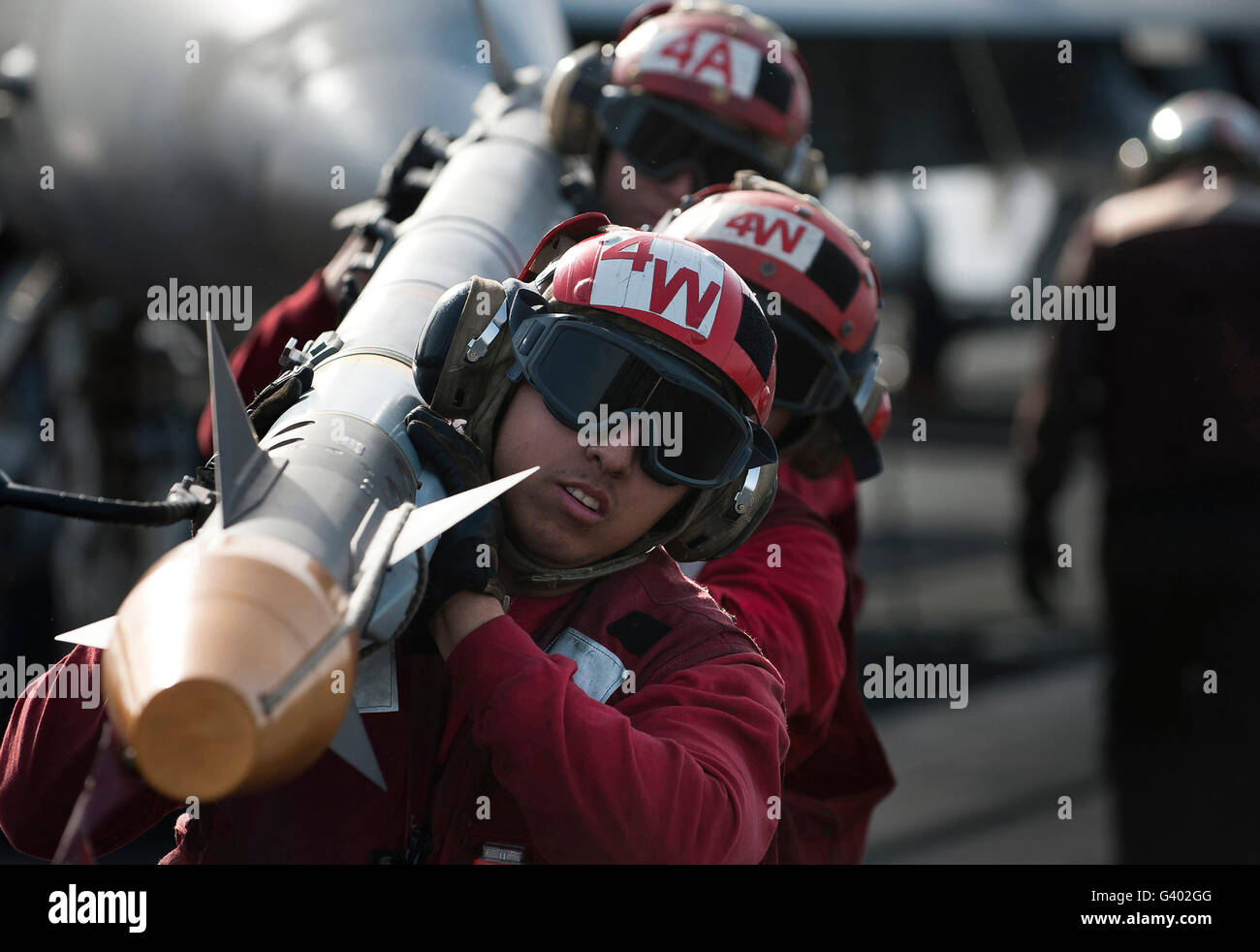 Aviation Ordnancemen carry an air-to-air missile on the flight deck. Stock Photo