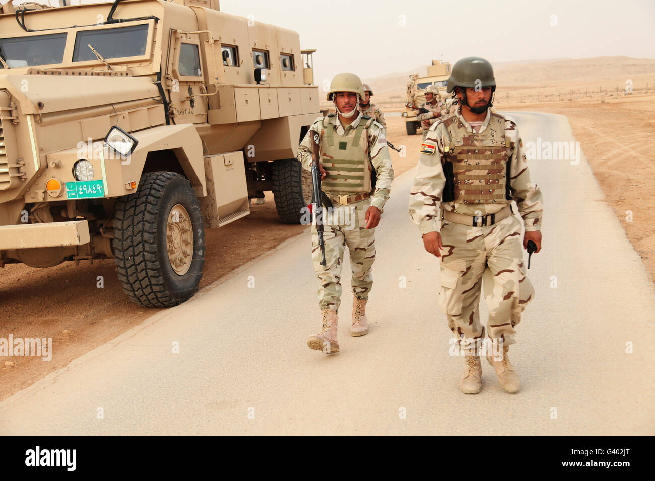 Iraqi army soldiers walk beside an MRAP vehicle in Iraq. Stock Photo