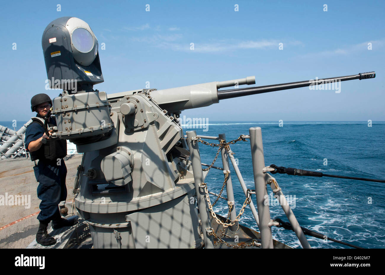 Gunner's Mate aims a 25mm chain gun aboard USS Cape St. George. Stock Photo