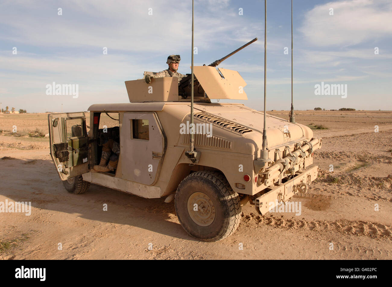 U.S. Army soldier pulls security on top of a M1114 Armored HMMWV Stock Photo