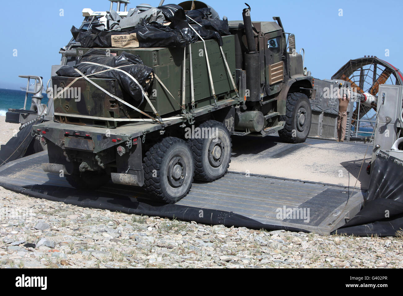 A Medium Tactical Vehicle Replenishment is loaded onto a Landing Craft Air Cushion. Stock Photo