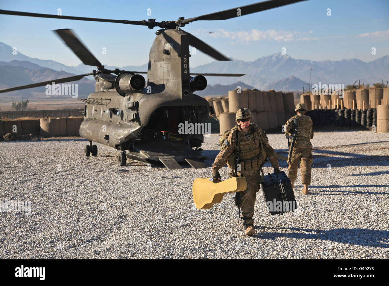 U.S. Army Sergeant helps unload band equipment from a CH-47 Chinook. Stock Photo