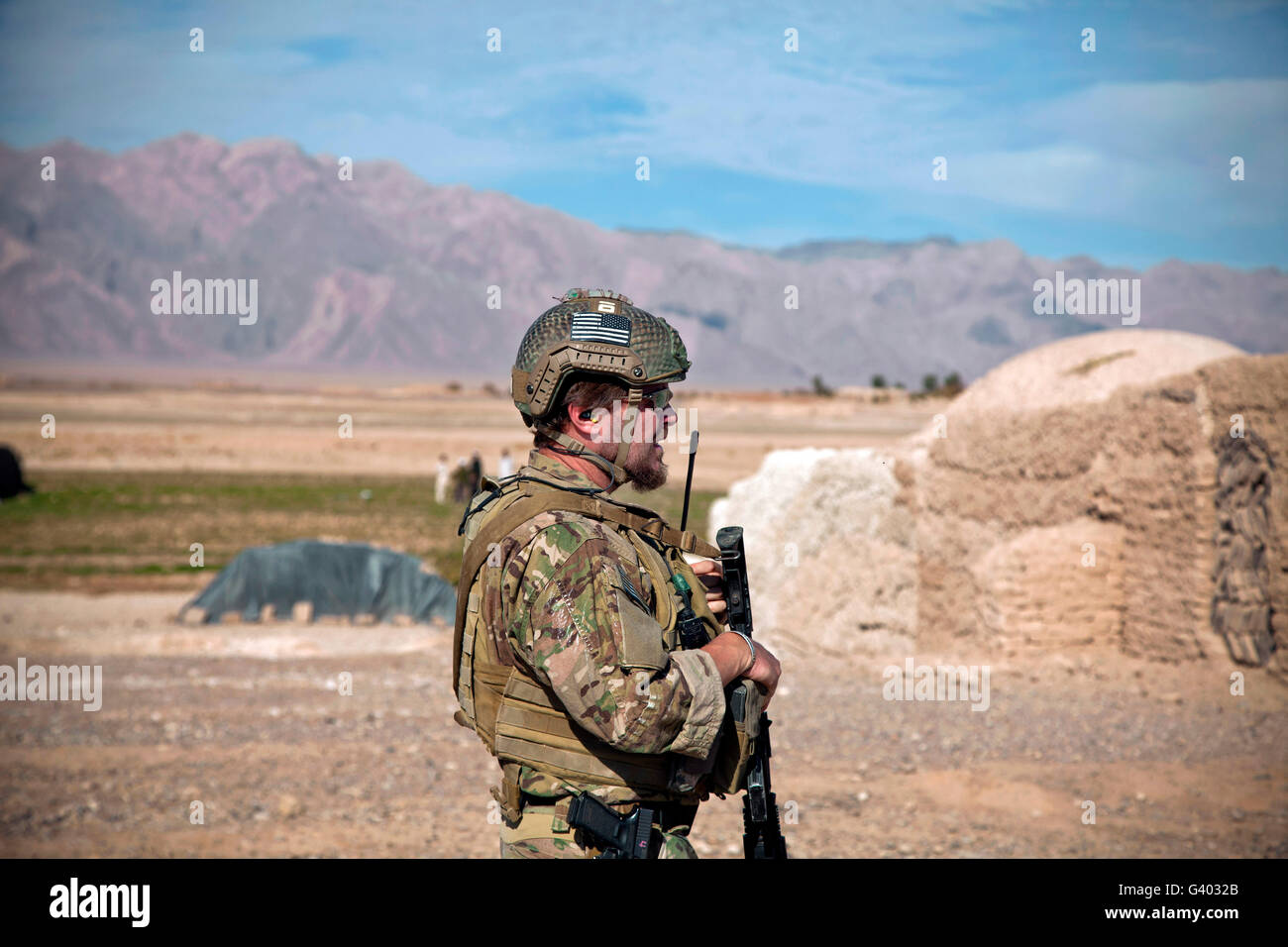 A coalition force member maintains security on the outskirts of an Afghan village. Stock Photo