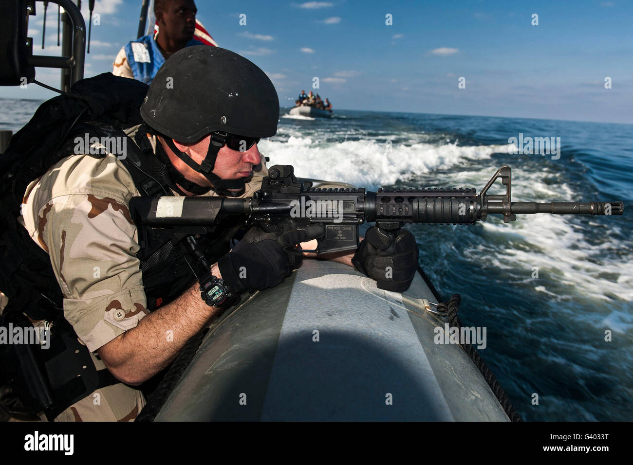 Soldier assumes a ready-to-fire position aboard a rigid-hull inflatable boat. Stock Photo