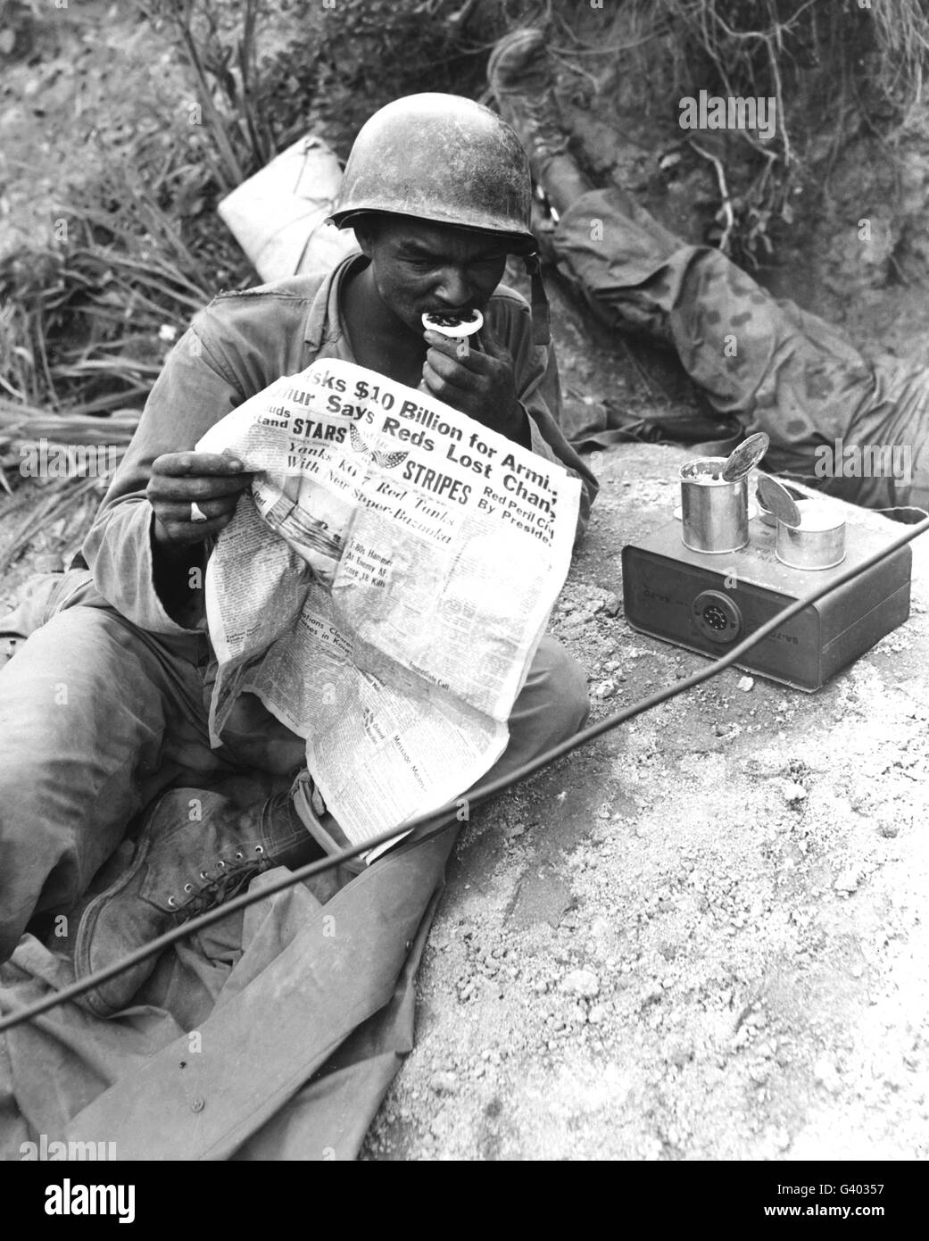 U.S. soldier reads the latest news while enjoying chow during a break in battle. Stock Photo