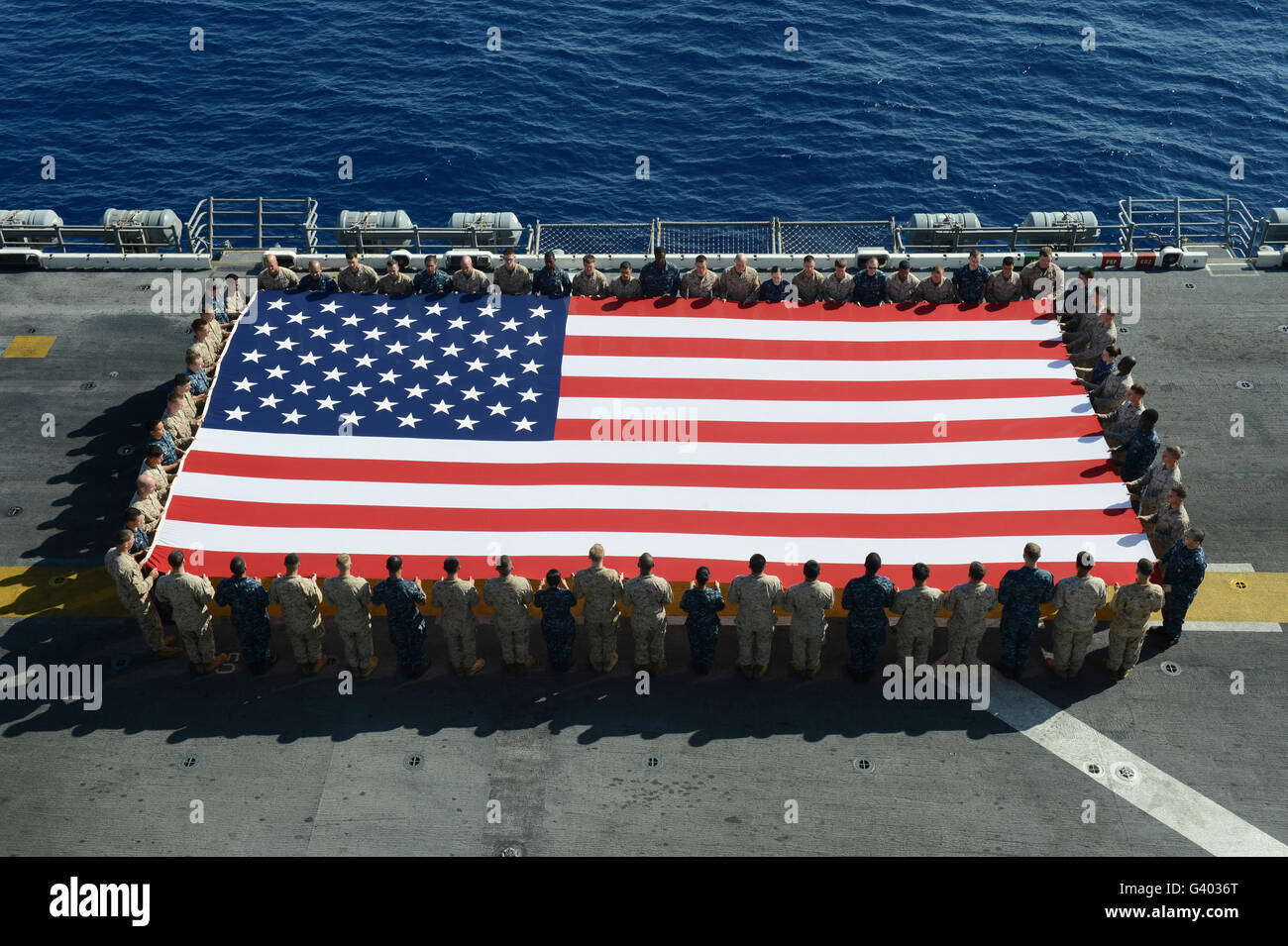 Sailors and Marines display the national ensign aboard USS Kearsarge. Stock Photo