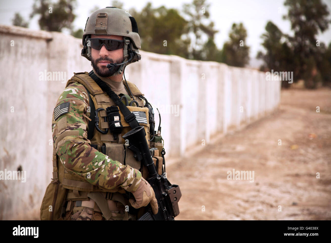 A coalition force member maintains security during a patrol. Stock Photo