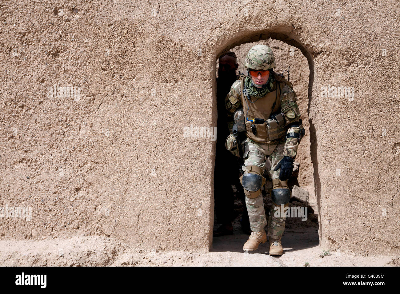 A Georgian Army soldier exits a compound in Afghanistan. Stock Photo