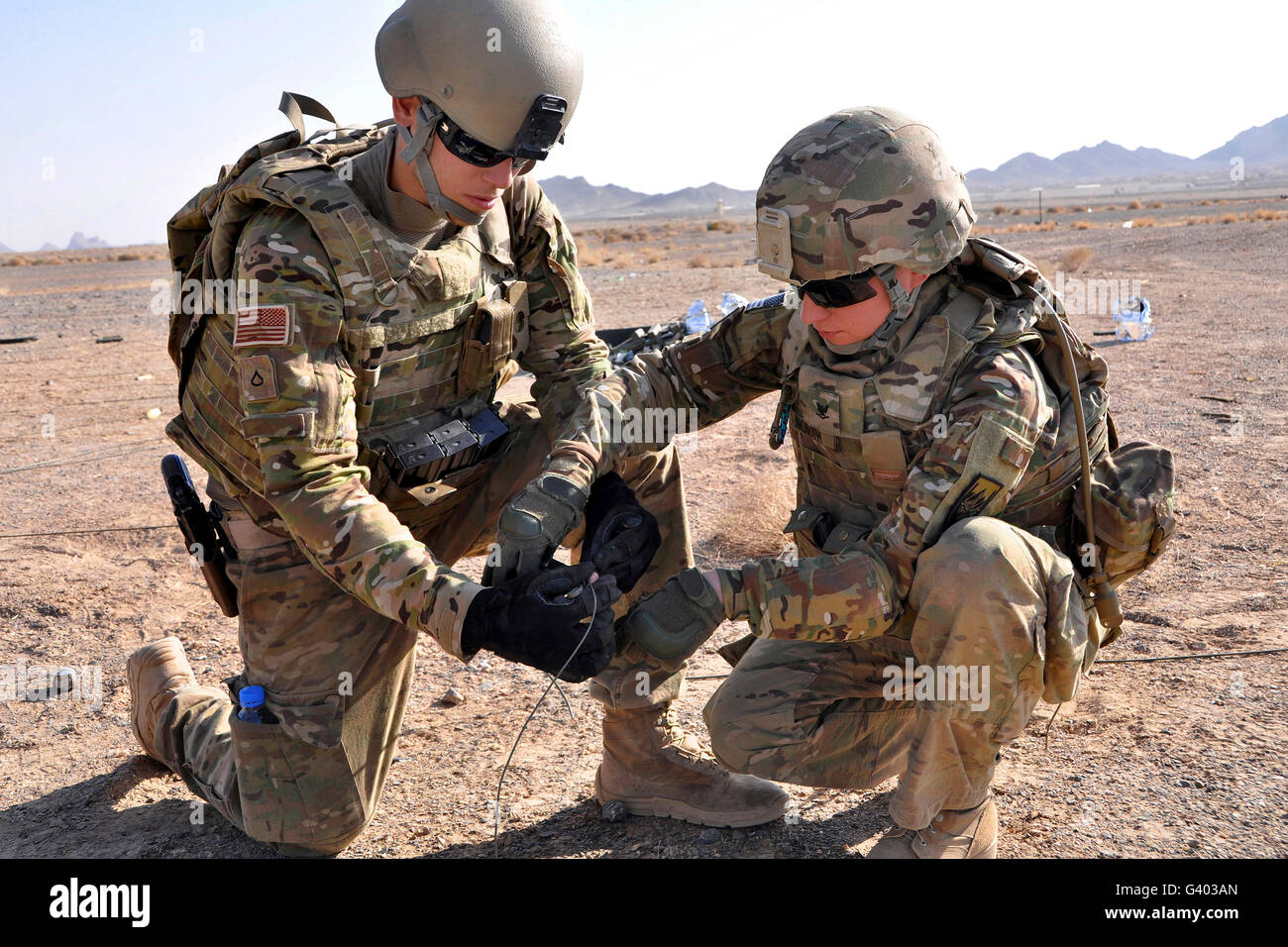 U.S. Soldiers use tape to wrap detonation cord together. Stock Photo