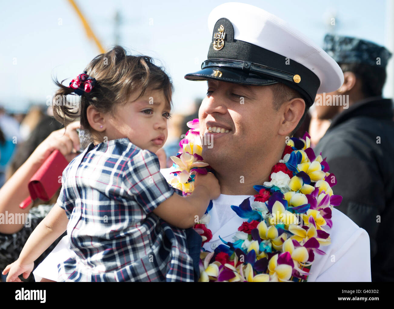 U.S. Navy sailor holds his daughter during a homecoming celebration Stock Photo