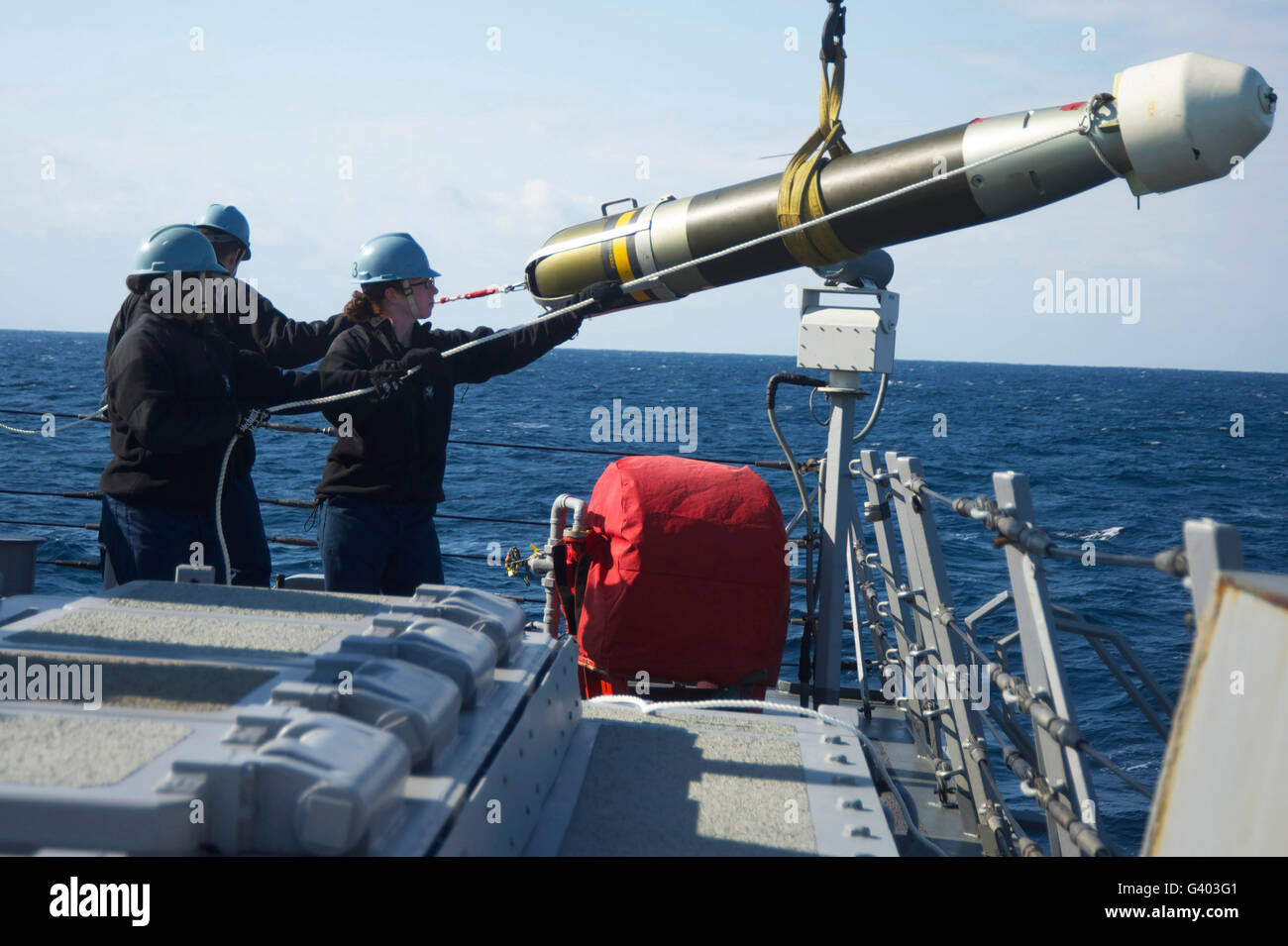 Sailors move a torpedo aboard USS Curtis Wilbur. Stock Photo