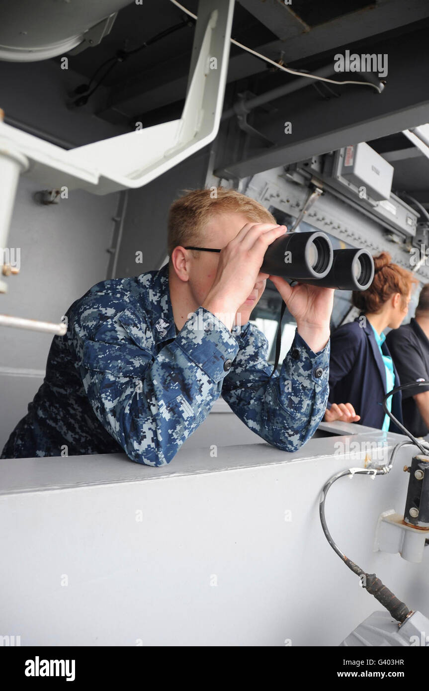 Intelligence Specialist looks at a surface contact through binoculars. Stock Photo