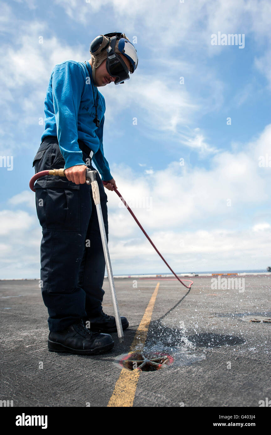 Airman uses lowpressure air to clean a pad eye on the flight deck of