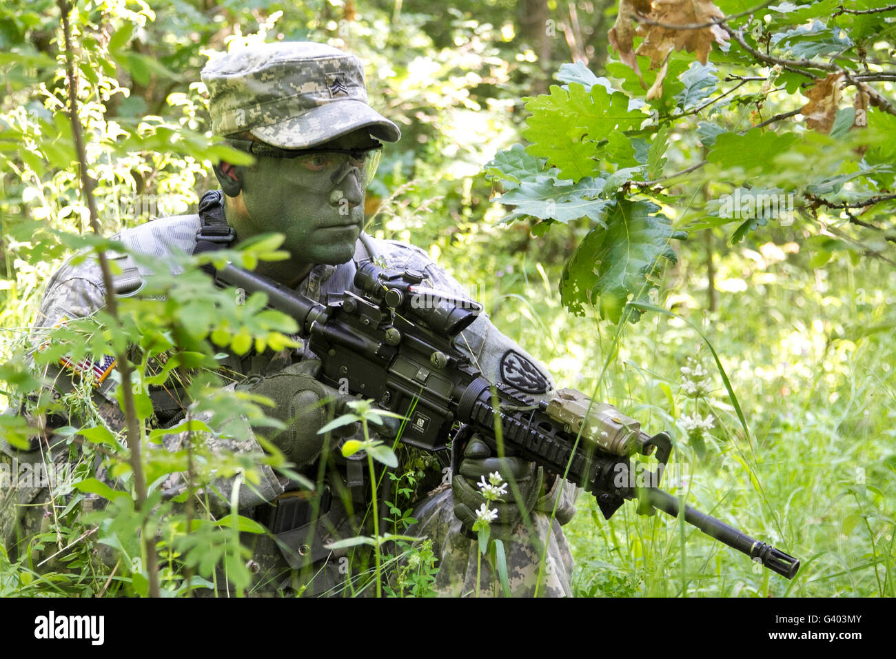 A soldier wearing face paint to blend in with the surrounding vegetation. Stock Photo