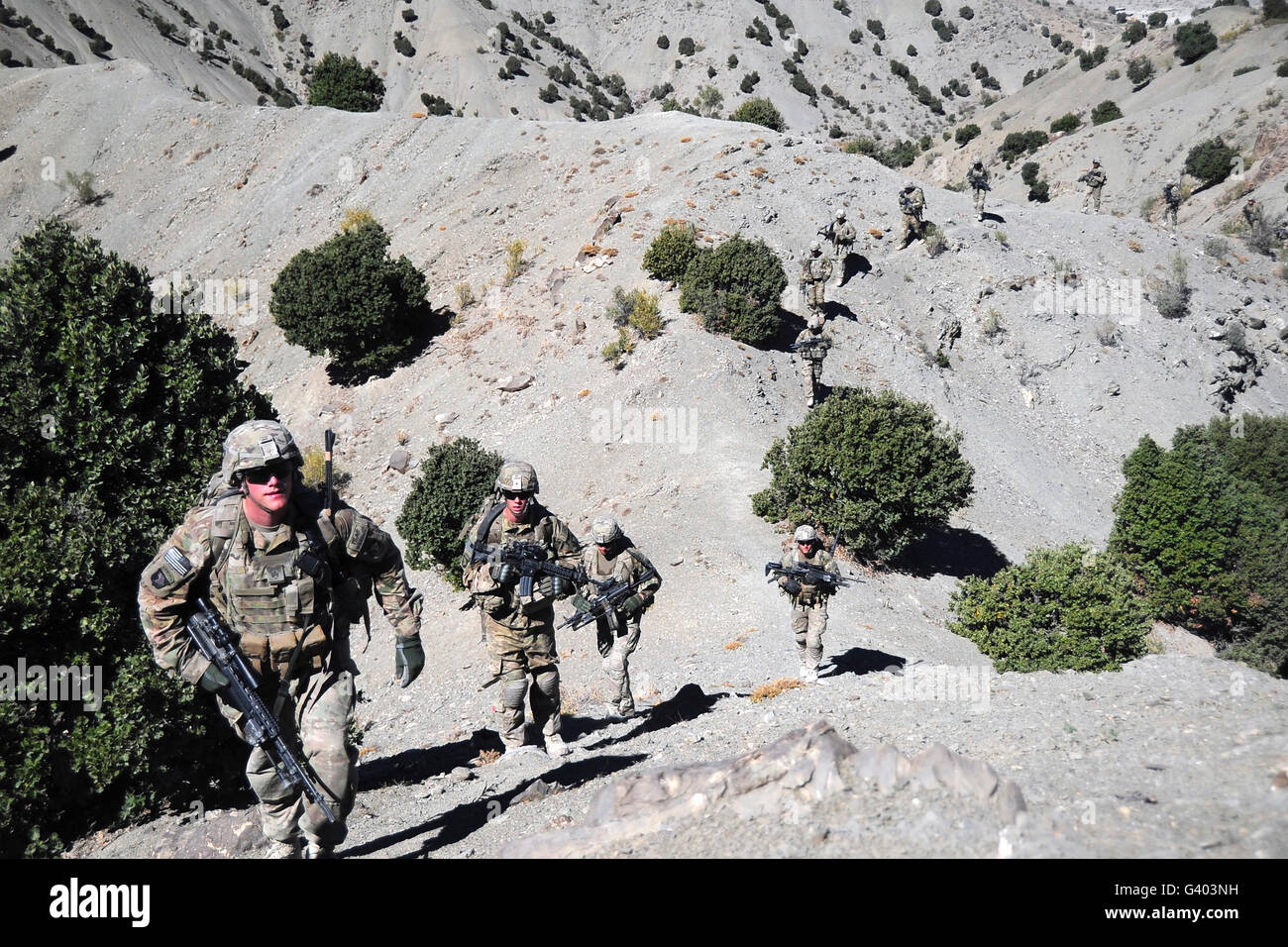 Infantrymen walk up a mountain trail in Afghanistan. Stock Photo