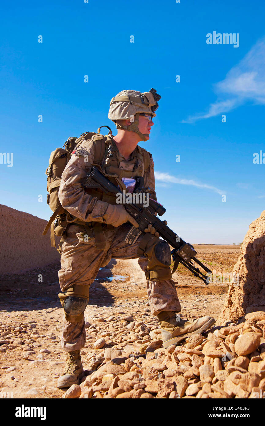 U.S Marine crouches behind a wall during a firefight. Stock Photo