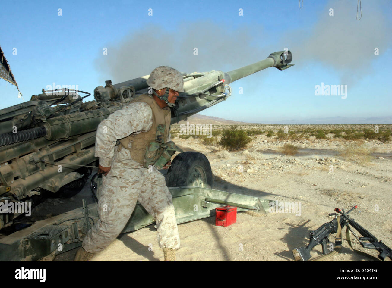 A cannoneer uses his body to pull the lanyard of a M777 Lightweight Howitzer. Stock Photo