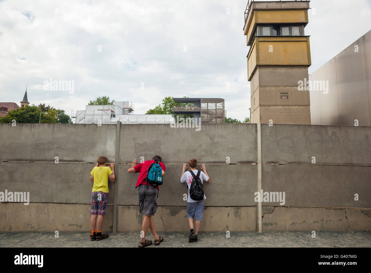 A family peeking through the Berlin wall memorial. Stock Photo