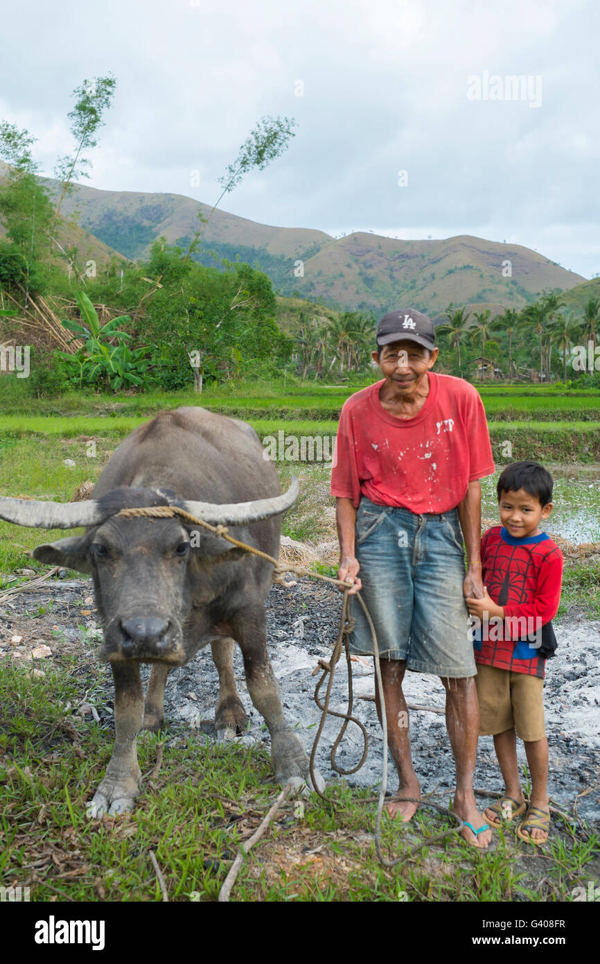 Grandfather and grandson posing with their water buffalo in the Philippines. Stock Photo