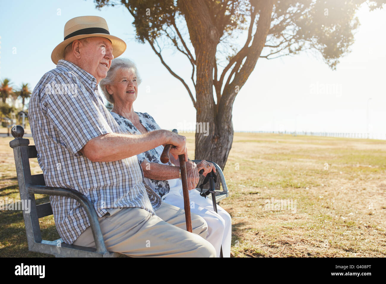 Side view shot of senior man and woman sitting on a park bench outdoors ...
