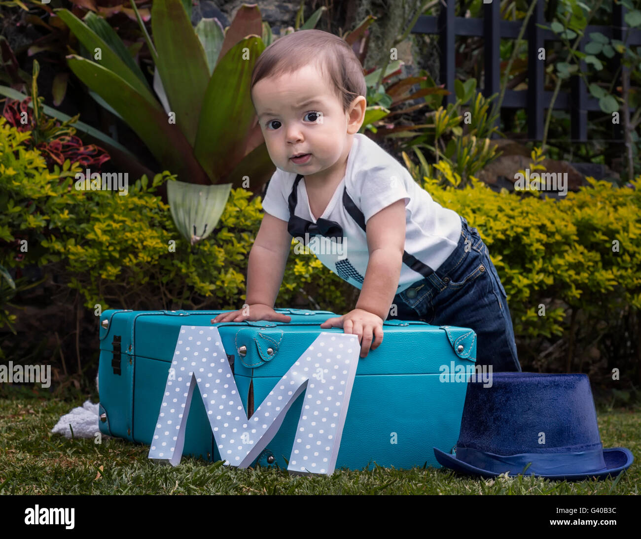 One year baby boy standing in a luggage in the garden Stock Photo