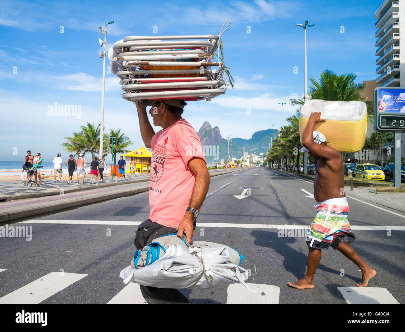 RIO DE JANEIRO - MARCH 20, 2015: Workers carry supplies to their barraca (beach stand) across beachfront Avenida Vieira Souto. Stock Photo