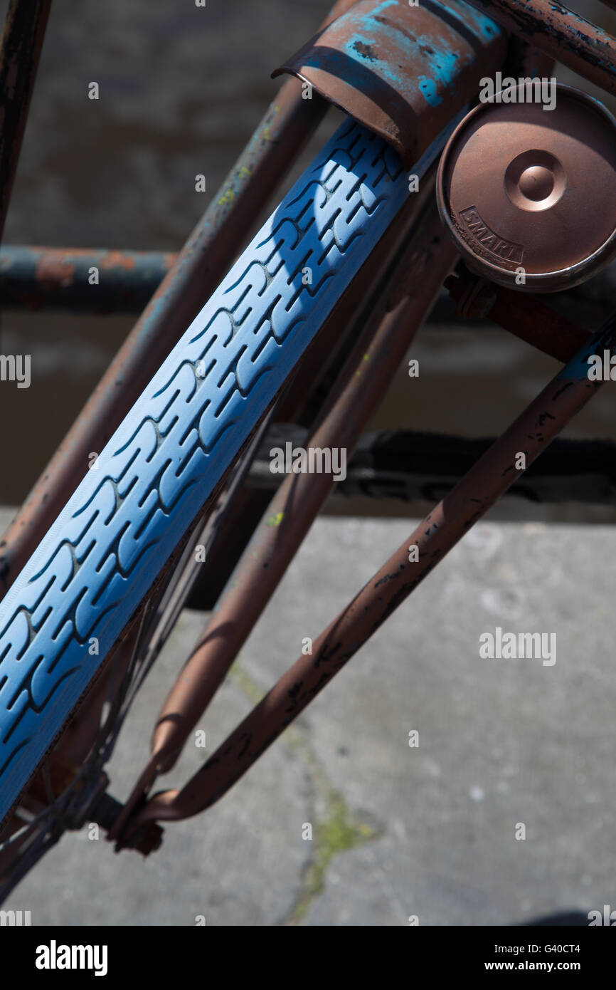 Close up of an old rusty front wheel of a bicycle with a blue tire in downtown Amsterdam, Netherlands. Stock Photo