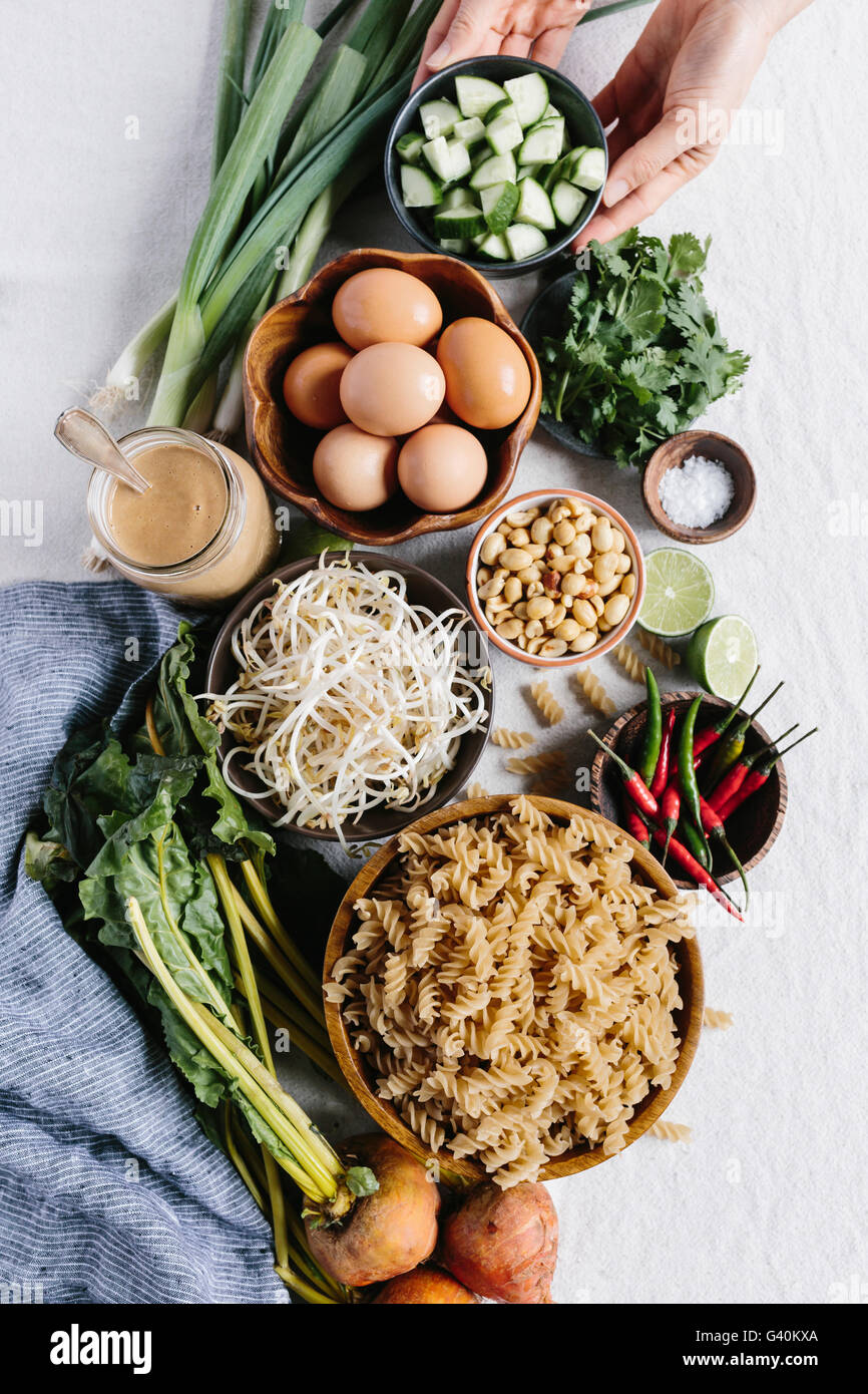 Ingredients for Crunchy Veggie Bowl with Warm Peanut Dressing are photographed from the top view (with hands). Stock Photo