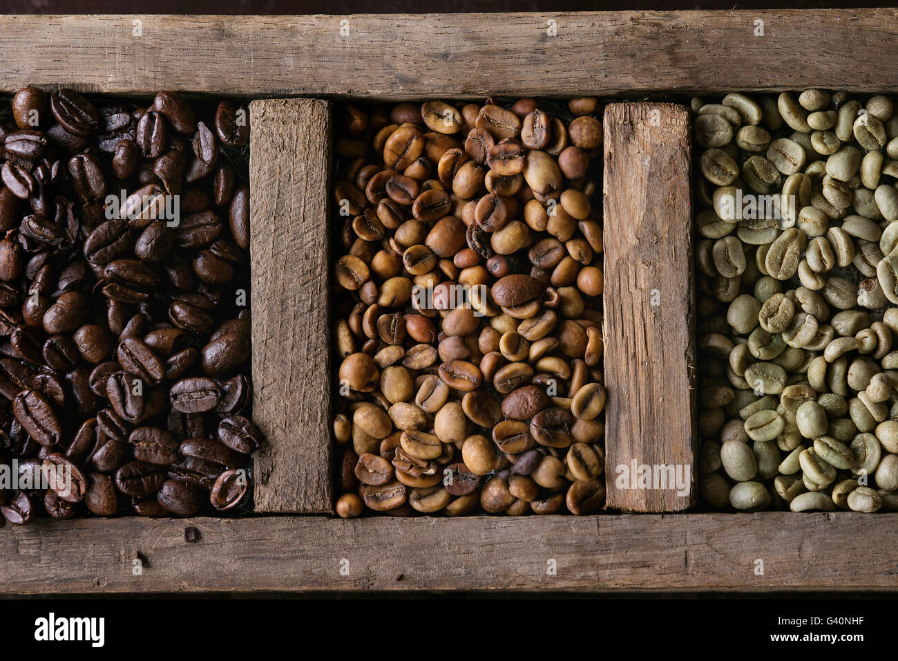 Food background with green and brown decaf unroasted and black roasted coffee beans in old wooden box. Top view. Close up Stock Photo