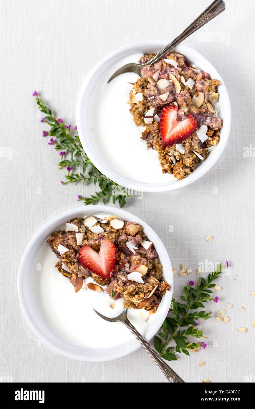 Two bowls of Strawberry and Rhubarb Breakfast Oat Crisp are served over yogurt and topped off with a sliced strawberry. Photogra Stock Photo