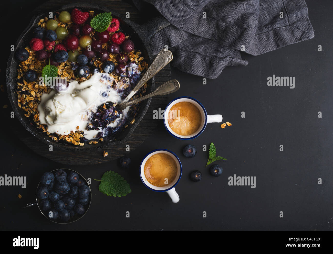 Healthy breakfast. Oat granola crumble with fresh berries, seeds and icecream in iron skillet