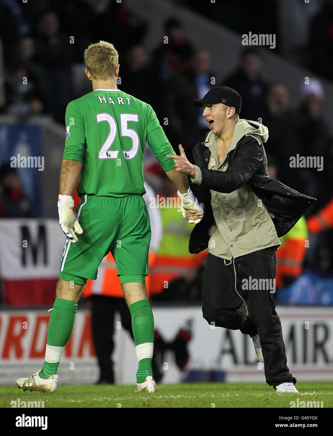 A pitch invader attempts to celebrate with Manchester City goalkeeper