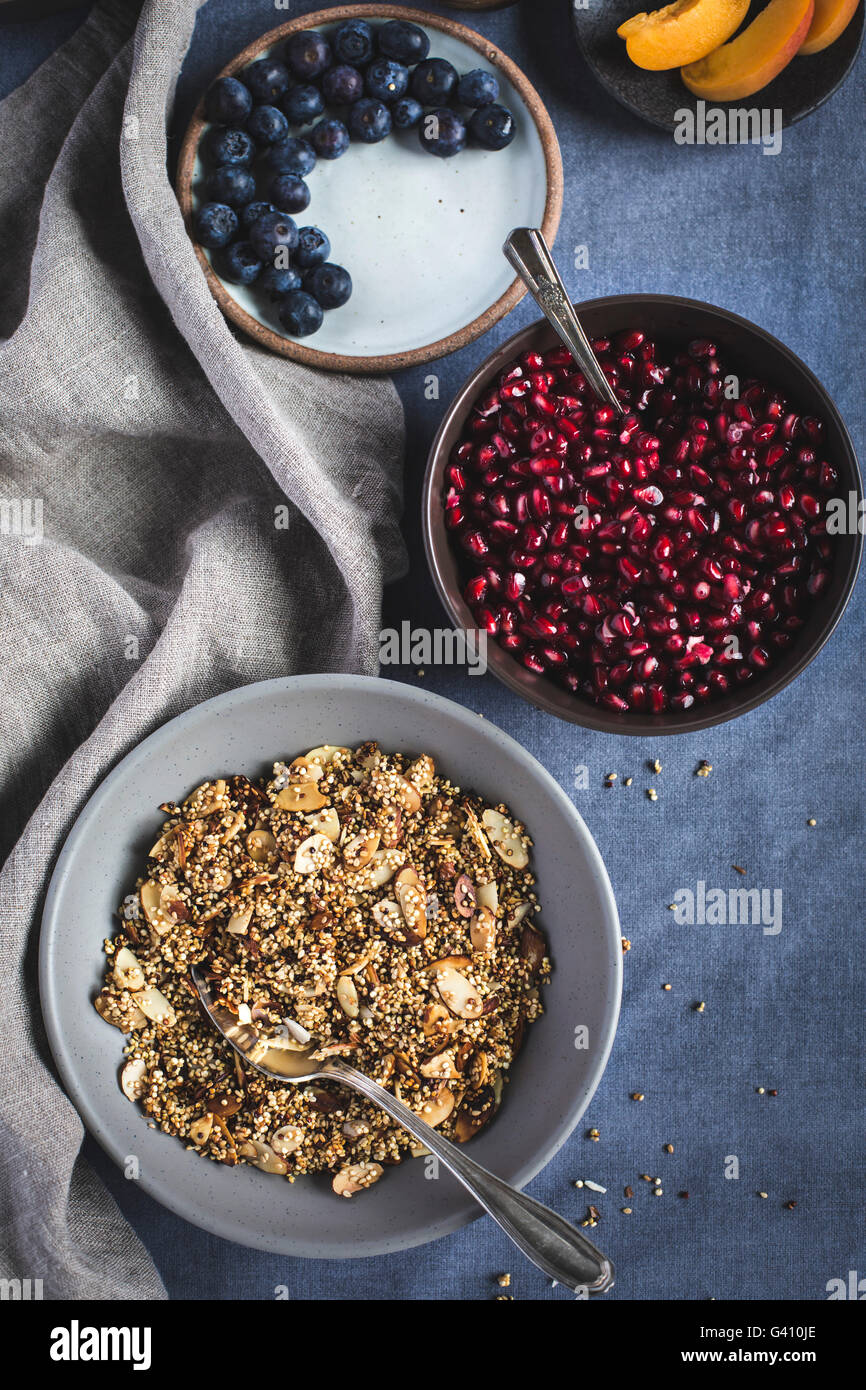 A bowl of quinoa crunch surrounded with pomegranate seeds and sliced apricots photographed from the top. (closer look) Stock Photo