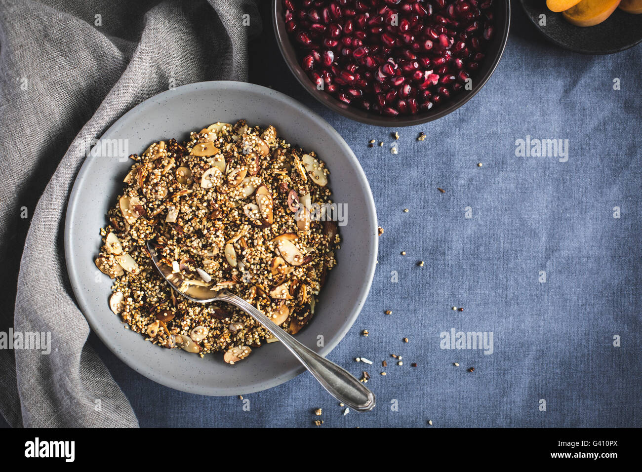 A bowl of quinoa crunch surrounded with pomegranate seeds and sliced apricots photographed from the top. Stock Photo