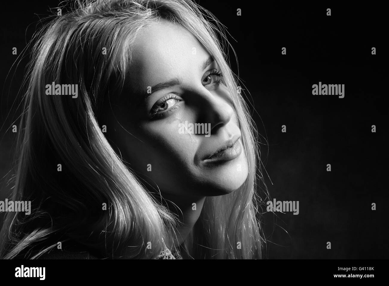 sad girl crying on black background, monochrome Stock Photo