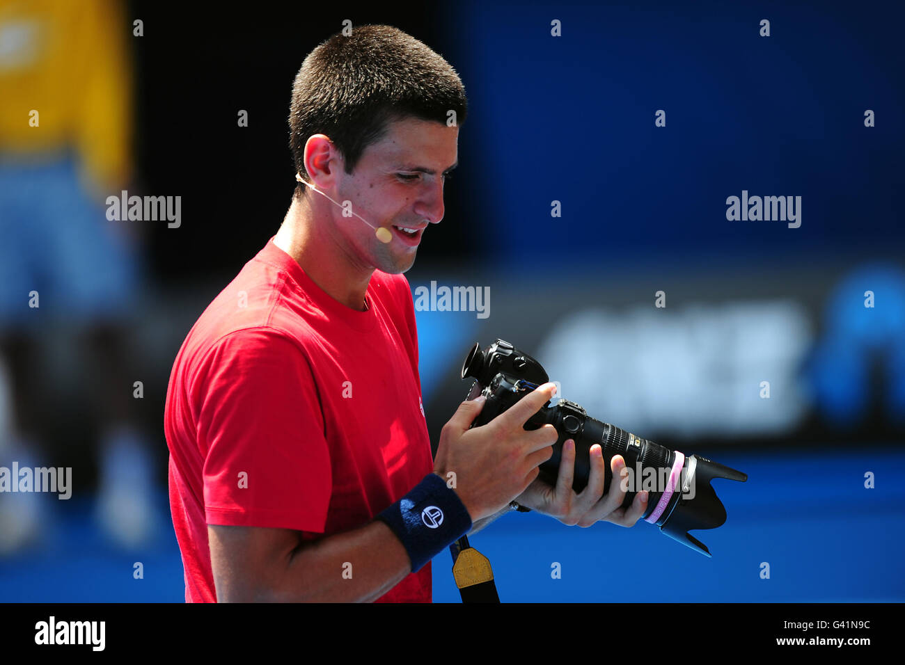 Serbia's Novak Djokovic plays with a photographers camera during a charity exhibition match in aid of Queensland flood victims Stock Photo
