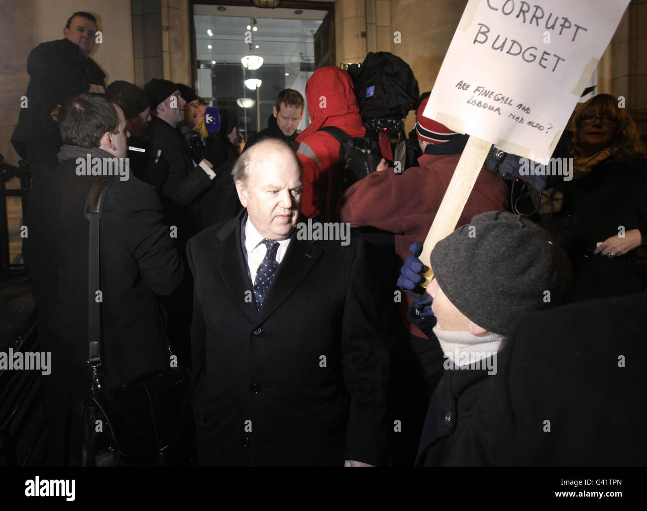 Fine Gael's Michael Noonan is confronted by a protester outside the Finance department on Merrion row in Dublin. Ireland's minority Government tonight secured support from the Opposition parties to pass the Finance Bill and dissolve parliament next week. Stock Photo