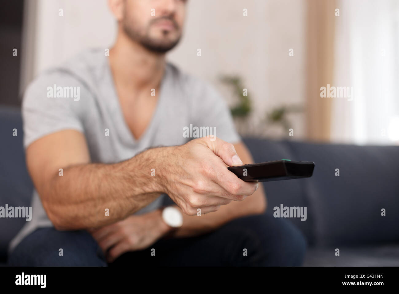 Man chaning TV channel by remote control at home Stock Photo