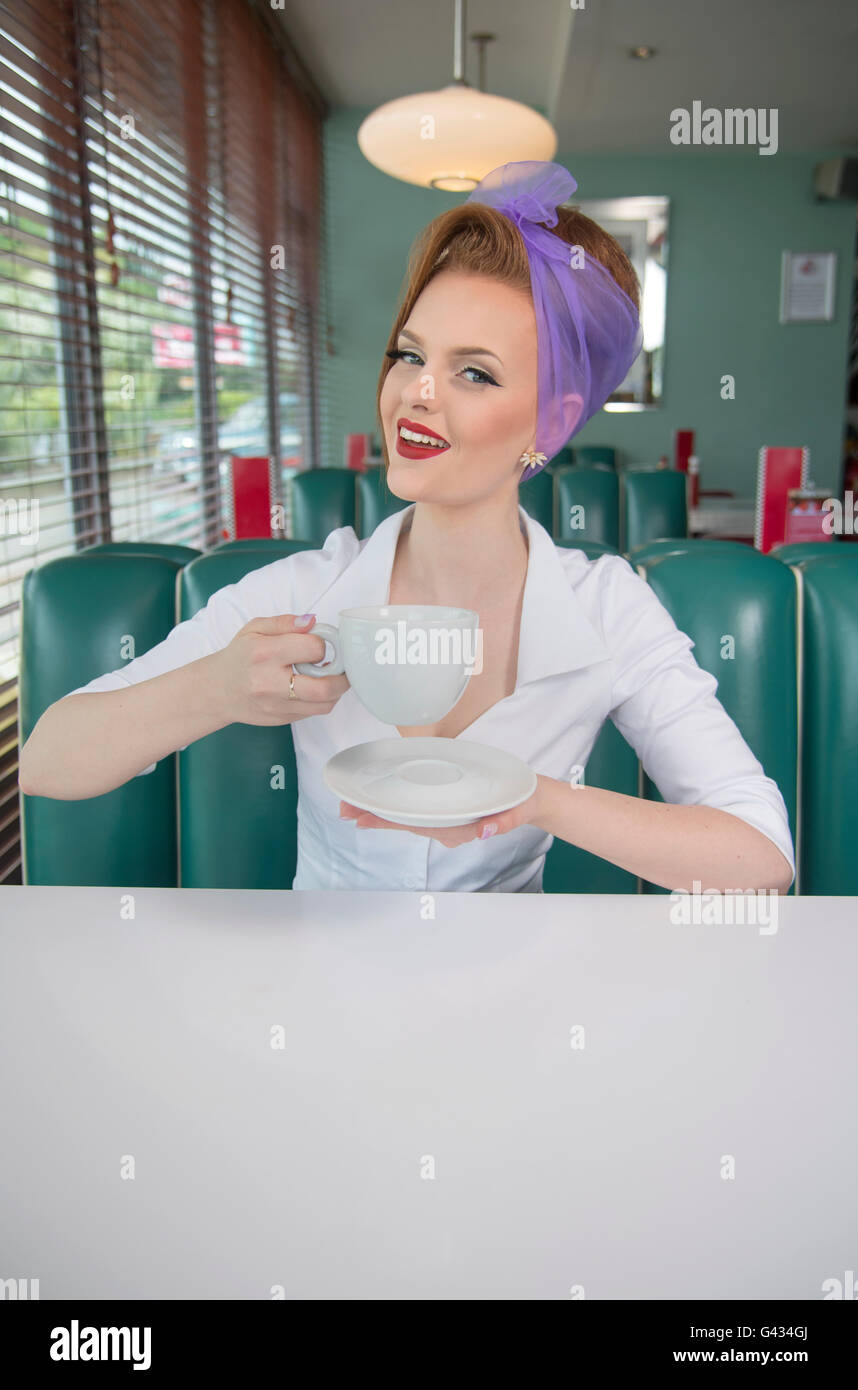 1960s look pin up girl in an American diner smiling with a coffee cup ...